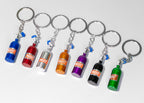 Set of colorful keychains shaped like miniature bottles on a white background