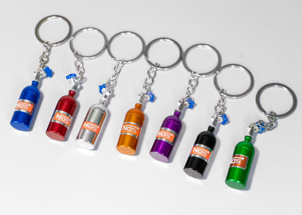 Set of colorful keychains shaped like miniature bottles on a white background