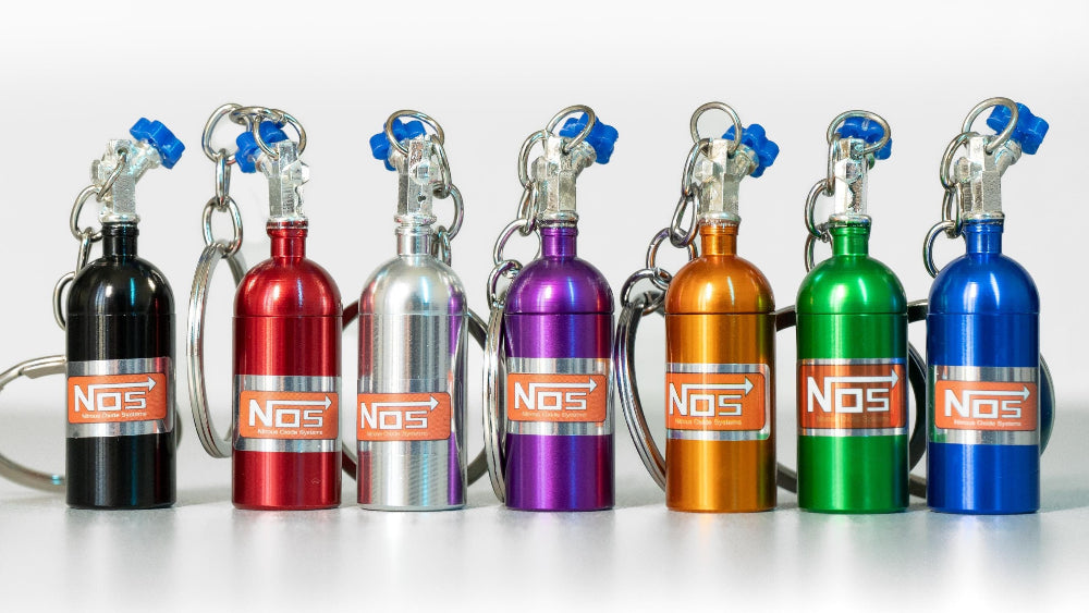 Set of colorful NOS (Nitrous Oxide Systems) canisters on a white background