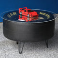 Round black table with a red toy car on a reflective surface against a blue wall.