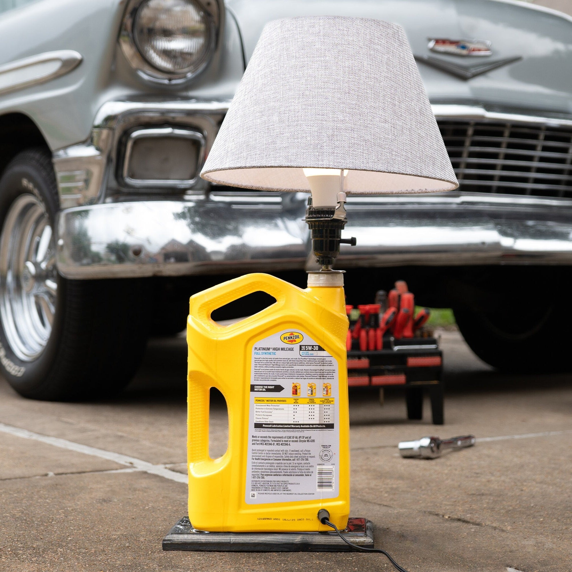 Yellow oil jug on a car lift with a classic car in the background