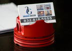 Red business card holder with a business card displaying '3G UNIQUE DECOR' on a dark surface.
