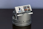 Business card holder shaped like a piston with a business card on a dark surface