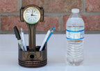 Desk organizer with clock and pens next to a water bottle on a white surface.