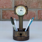 Piston-shaped clock and pen holder with pens on a white surface and brick wall background