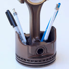 Piston-shaped pen holder with pens on a white background