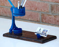Blue pen holder with business card stand on a white surface with brick wall background