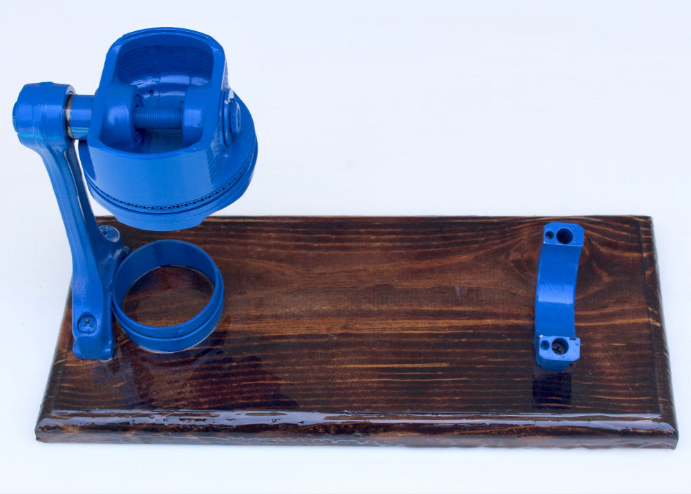Blue metal component on a wooden board against a white background