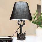 Black table lamp with a unique design on a desk next to a plant