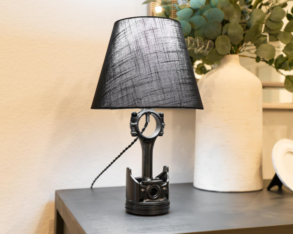Table lamp with black shade and unique base design on a wooden surface.