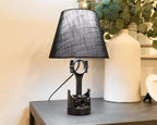 Table lamp with black shade and unique base design on a wooden surface.