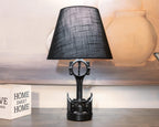 Black table lamp with a decorative base on a wooden surface.