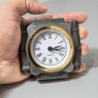 Hand holding a unique clock with a mechanical design on a neutral background
