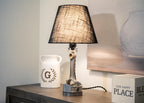 Table lamp with a black shade on a wooden surface next to a decorative container.