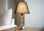 Table lamp with a black shade on a wooden table next to a white sofa.
