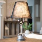 Table lamp with a dark fabric shade on a wooden surface, blurred indoor background