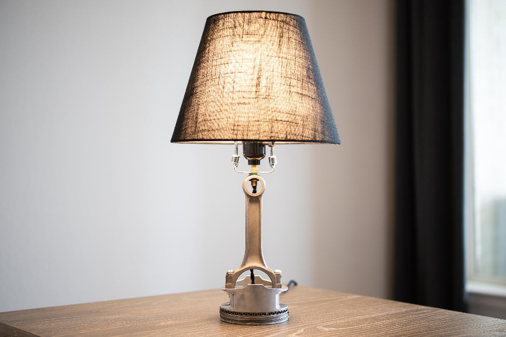 Table lamp with a textured shade on a wooden surface against a neutral wall.