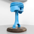 Blue piston on a wooden stand against a white background