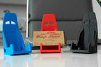 Three colorful phone stands on a reflective surface with a blurred background