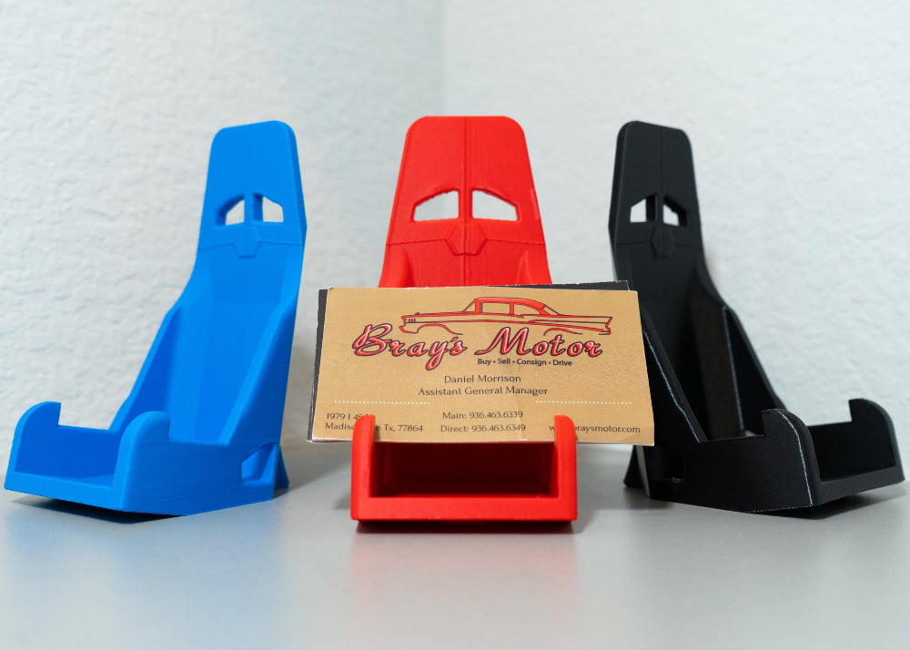Three car window holders in blue, red, and black with a cardboard sign in the center.