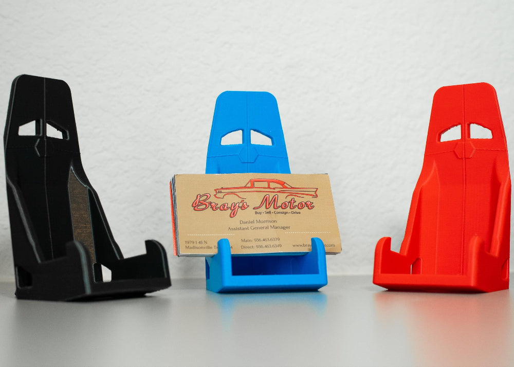 Three car seat racing harnesses in black, blue, and red with a business card holder in the center.