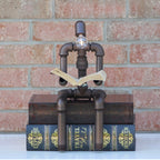 Decorative lamp made of pipes and books against a brick wall.