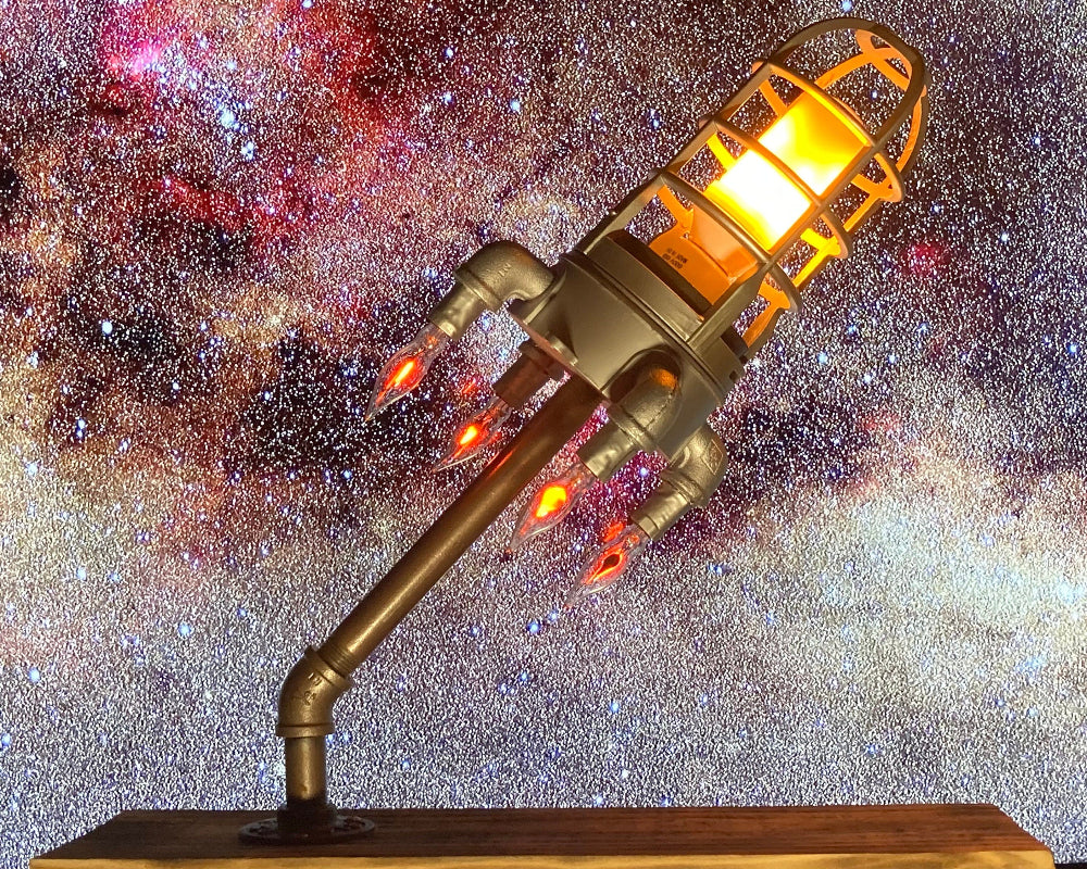 Decorative lamp resembling a rocket with glowing orange light against a starry space background