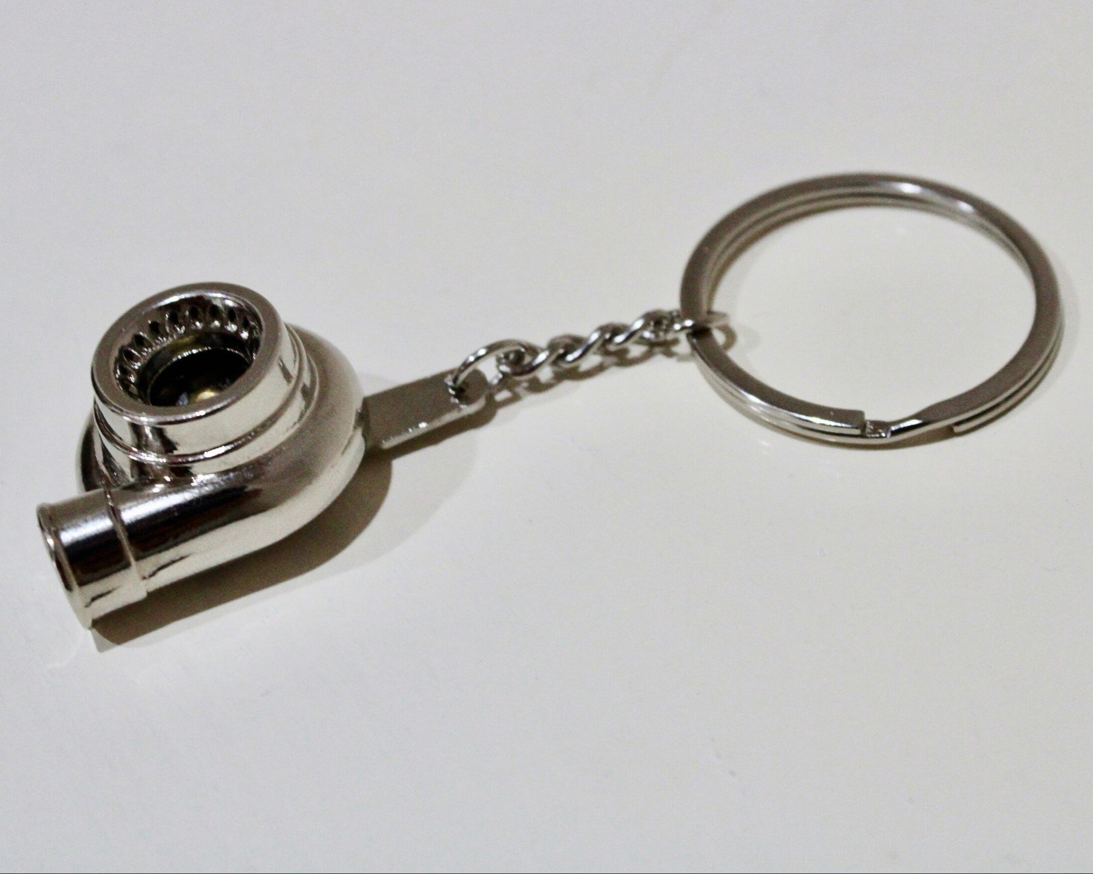 Metal keychain shaped like a turbocharger on a white background