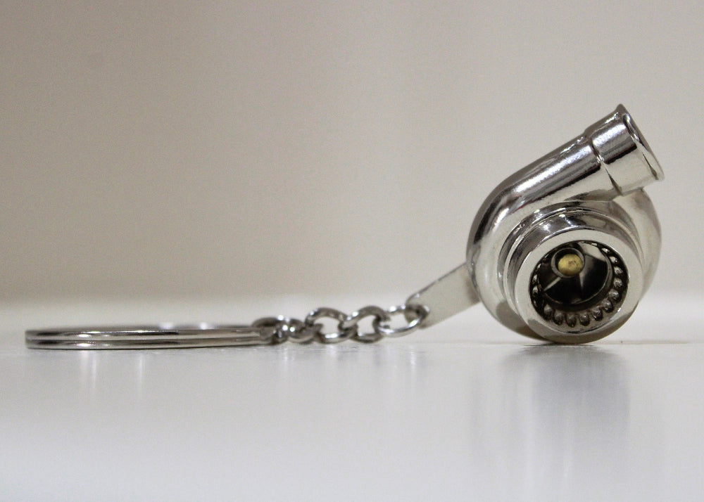 Turbocharger keychain on a white surface with a neutral background