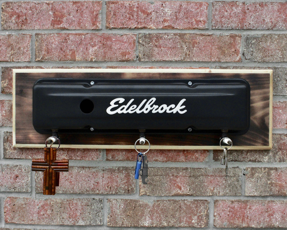 Decorative metal plate with 'Edelbrock' logo on a brick wall.