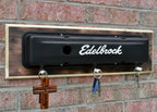 Key holder with 'Edelbrock' branding on a brick wall