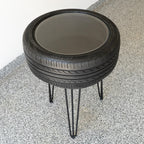 Table made from stacked tires with metal legs on a concrete surface