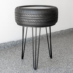 Side table made from a recycled tire on a concrete floor with a white wall background