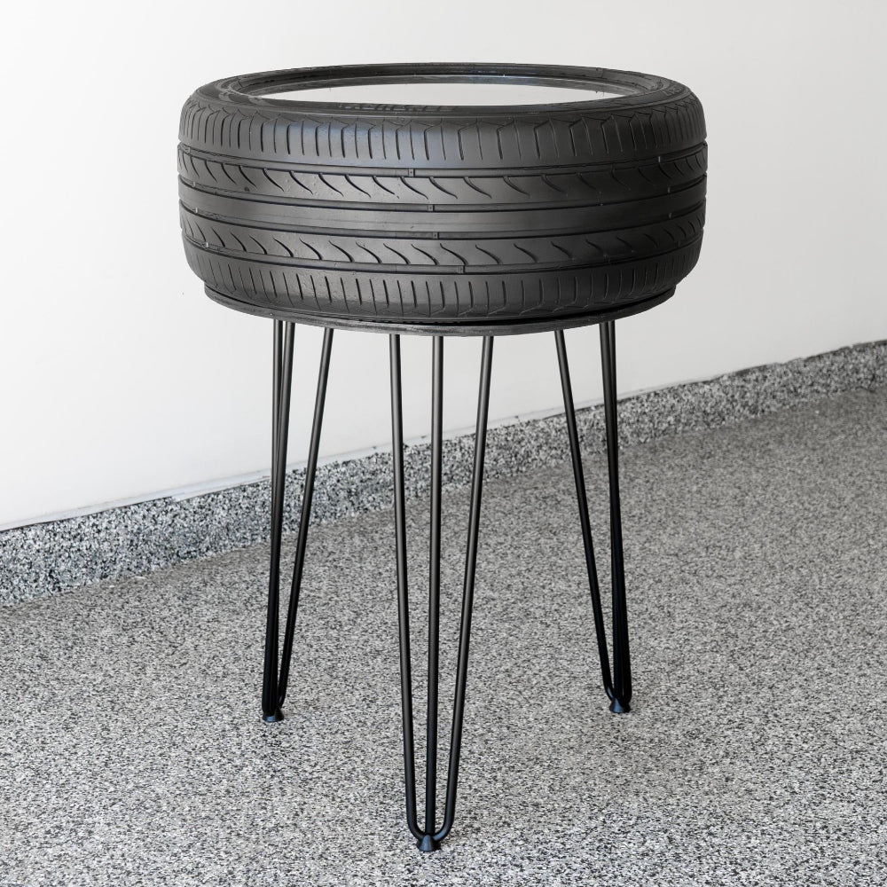 Side table made from a recycled tire on a concrete floor with a white wall background