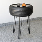 Table made from a recycled tire with hairpin legs on a concrete floor.