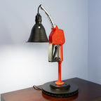 Table lamp designed like a vintage gas pump on a wooden surface with a light blue background