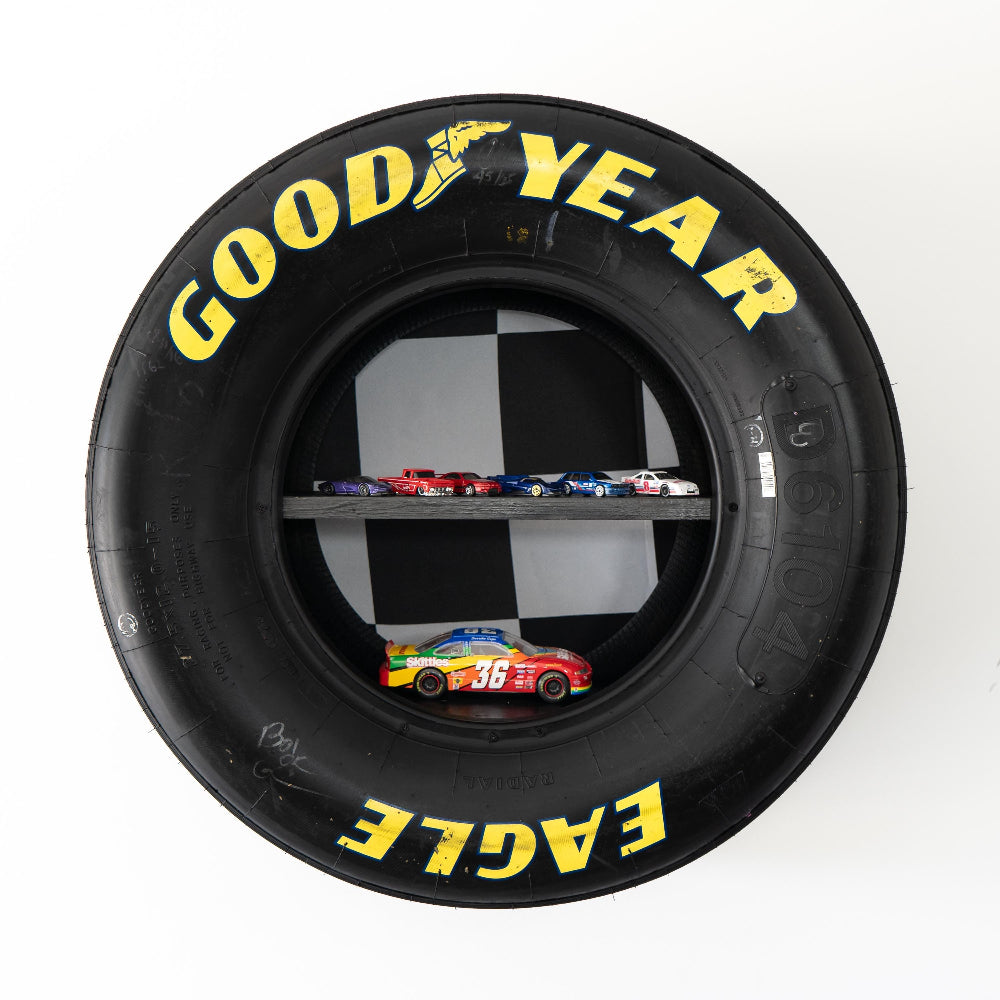 Wall shelf built from race used tire designed to display collectibles trophies and racing memorabilia.