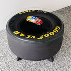 Black tire-shaped stool with 'Good Year' branding on a gray floor.